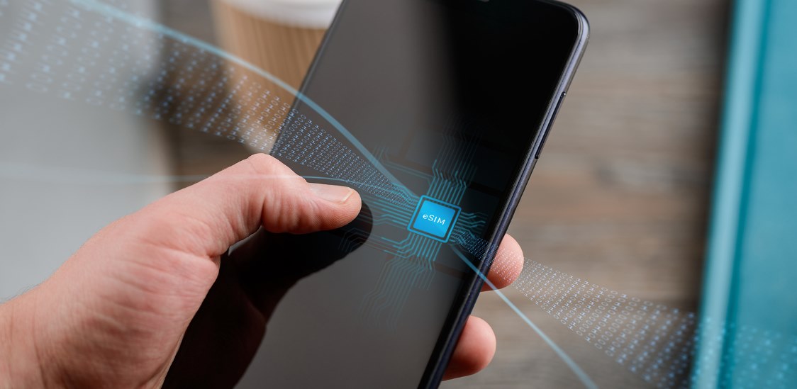 Hand holding a smartphone with a digital eSIM chip graphic on the screen.