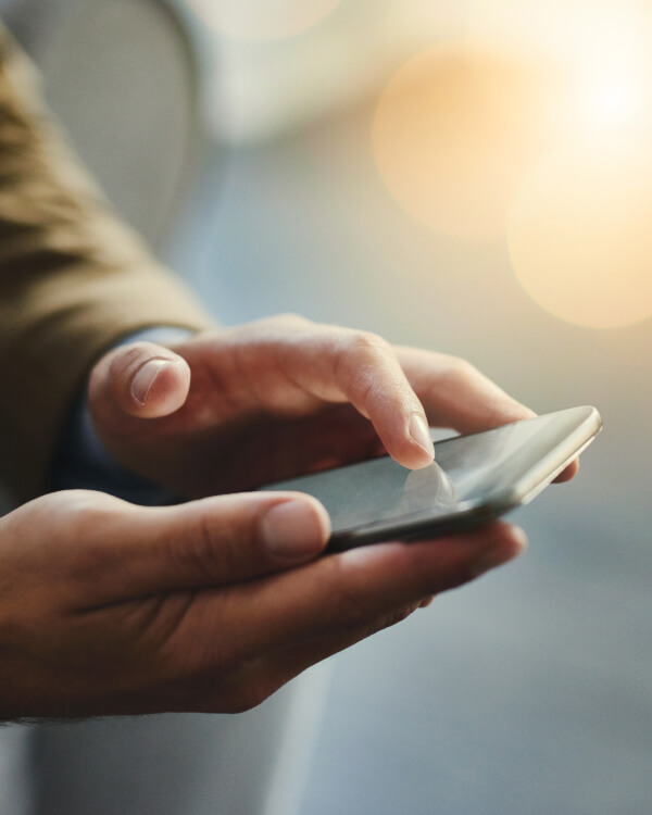 RiPSIM SPG.32 Scalable Architecture Close-up of a person using a smartphone with a blurred background and warm sunlight.