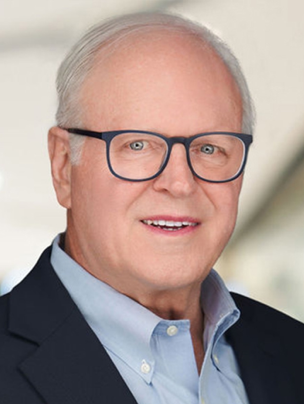 A middle-aged man with glasses, light-colored hair, and a friendly smile, wearing a dark blazer and light blue shirt.