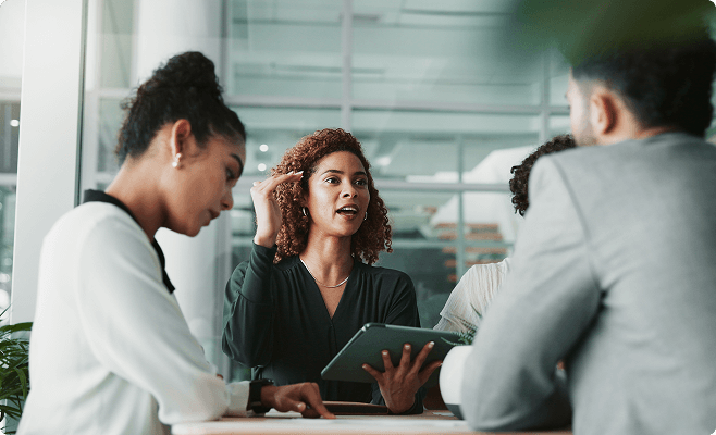 Ripsim-Company-Careers A woman in a black top discusses career opportunities with three colleagues in a modern office setting.