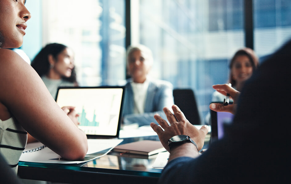 People in a business meeting discuss data and strategies in a modern office setting.